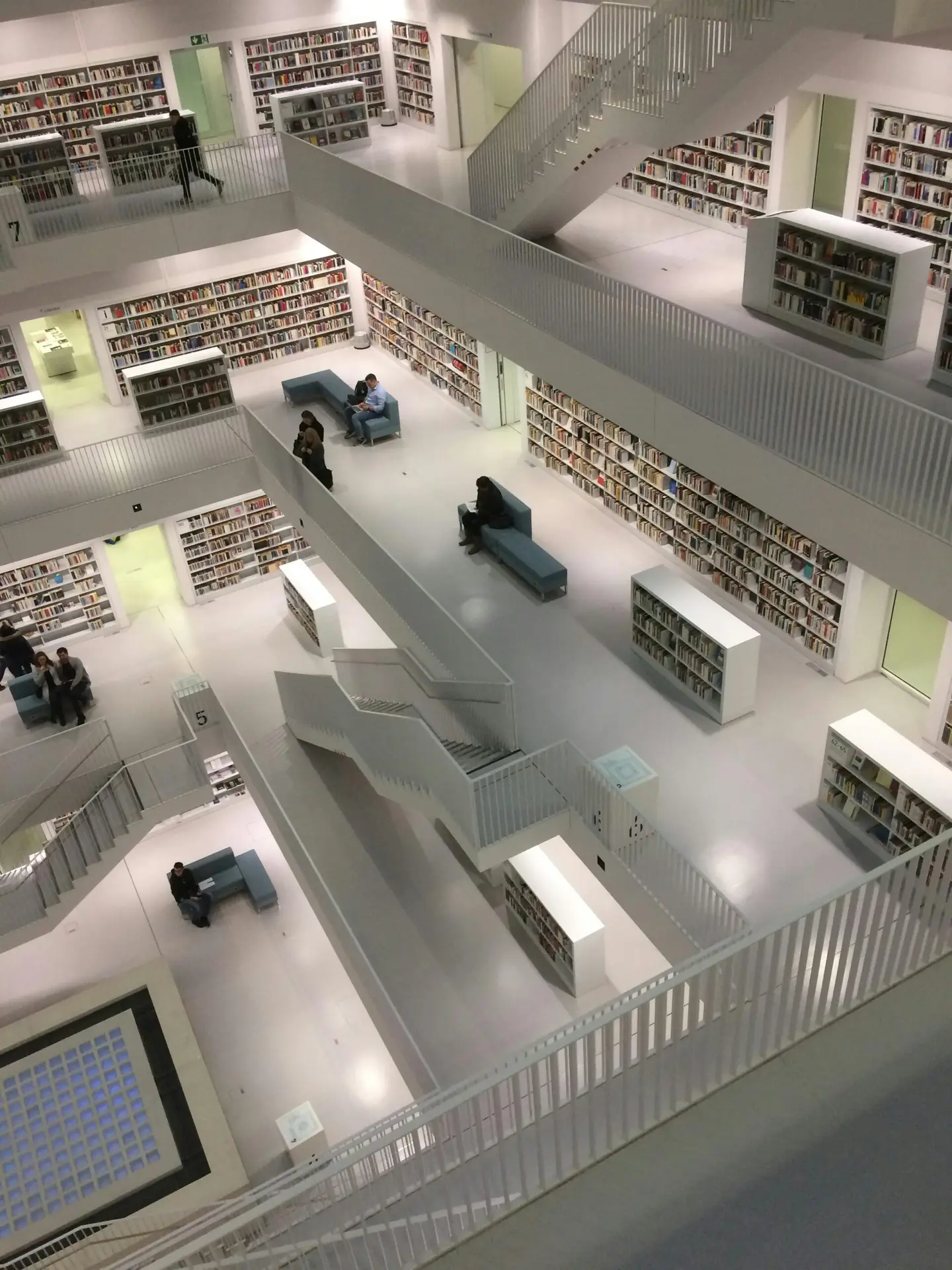 A multi-level library interior with modern architecture, bookshelves, and minimalistic white design.